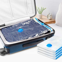 Vacuum storage bags on bedding inside blue travel suitcase with pump and folded bags