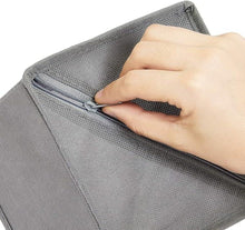 Gray cloth storage box with zippered opening, hand gripping edge