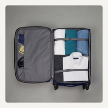 Softside navy suitcase open showing compartments and bundled clothing inside
