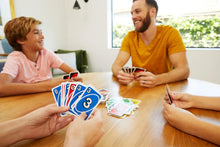 UNO card game hands holding colorful UNO cards on a table