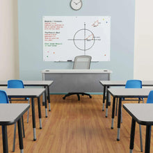 White glass dry-erase board on wall with marker tray and circular chart on surface