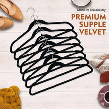 Black velvet clothes hangers with metal hooks, stacked on a flat surface