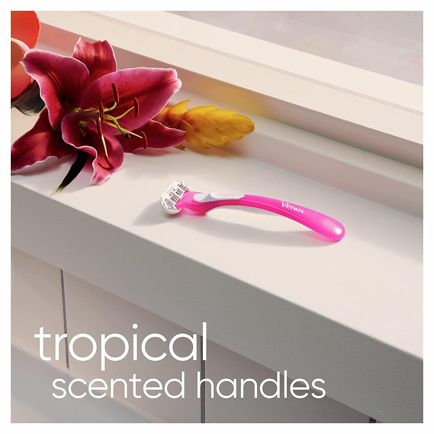 Pink Gillette Venus Tropical women's razors on windowsill with tropical flower and scented handle