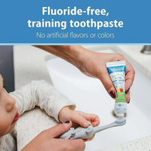Fluoride-free baby toothpaste tube being used with training toothbrush