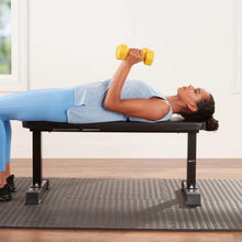 Black flat workout bench used for dumbbell glute bridge exercise