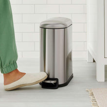 Stainless steel trash can with open lid and black foot pedal near floor