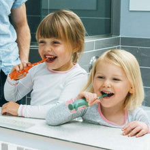 Children brushing with green training toothbrush, fluoride-free toothpaste on bristles