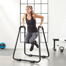 Dip fitness bar in use, black steel frame with foam grips and foot pads