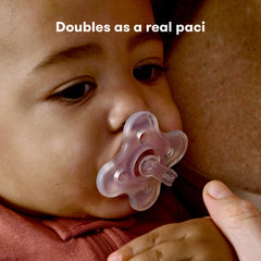 Close up of baby using Frida Baby MediFrida Accu-Dose Pacifier held by caregiver clear silicone pacifier for soothing