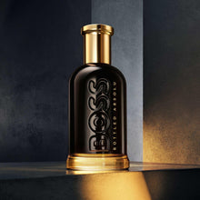 Parfum bottle with black glass and gold cap, embossed BOSS logo.