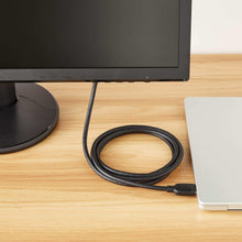 Black HDMI cable coiled on desk with connector end visible