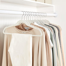 Set of ivory velvet suit hangers on a closet rod with silver hooks