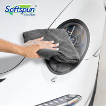 Grey microfiber cloth folded, held against a washing machine door