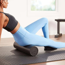 Foam roller used under leg during stretching, textured black cylinder