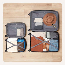 Open black hard-sided suitcase set showing two packing compartments with straps