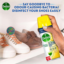 Disinfectant spray bottle held near brown shoes with orange laces
