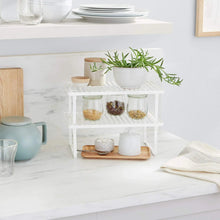White metal stackable shelf holding jars and containers on two slatted levels