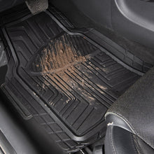 Black rubber floor mat in car holding debris, with deep grooves and raised channels
