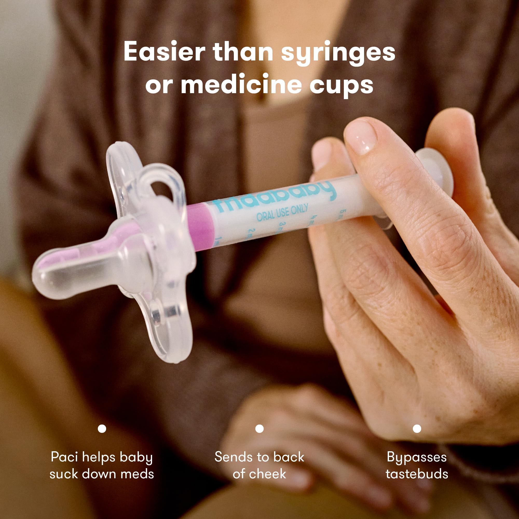 Frida Baby MediFrida Accu-Dose Pacifier held by adult dispensing medicine to baby with shield and syringe tube