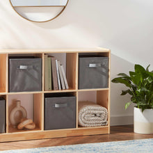 Grey collapsible fabric storage cubes with handles in a wooden shelving unit