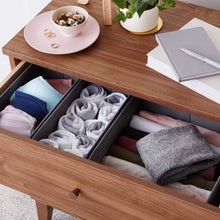 Gray cloth drawer organizer boxes holding folded socks and fabric pieces