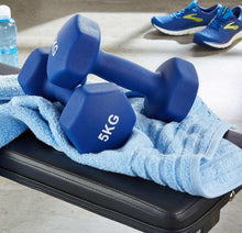 Blue 5KG neoprene dumbbells on black workout bench with towel.