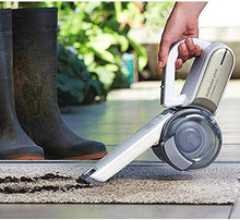Cordless handheld vacuum with pivoting nozzle on a floor surface, clear dust canister