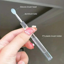Silicone makeup brush with white oval tip, clear cap, and silver handle tube