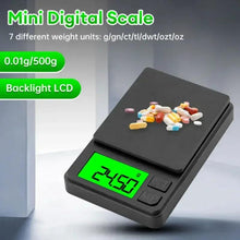 Mini digital gram scale on dark platform with green backlit LCD and scattered items