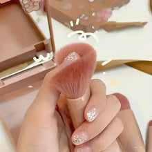 Mini makeup brush with full round rose-beige bristles in a compact case