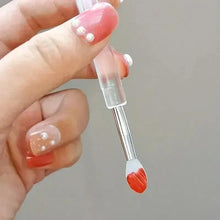 Silicone lip brush with clear handle and orange-red oval tip held in hand