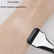 Foundation brush with black bristles and silver handle, spreading makeup on skin