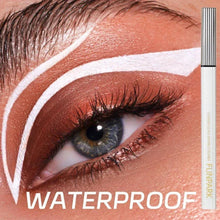 White liquid eyeliner pen beside eye makeup, bold white graphic wing and arc