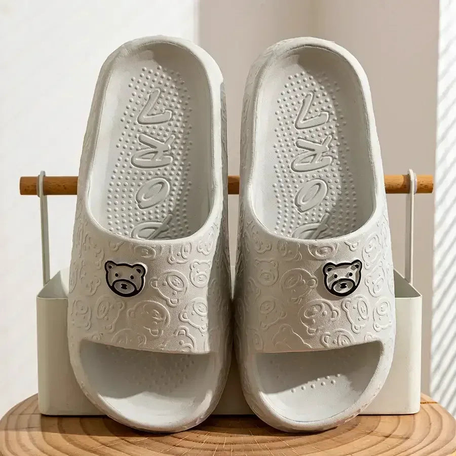 White slide sandals with bear logo and textured footbed