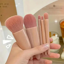 Five mini makeup brushes with rose-beige handles held in one hand