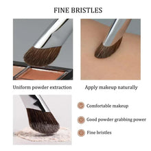 Makeup brush with fine brown bristles on a silver ferrule, shown applying powder