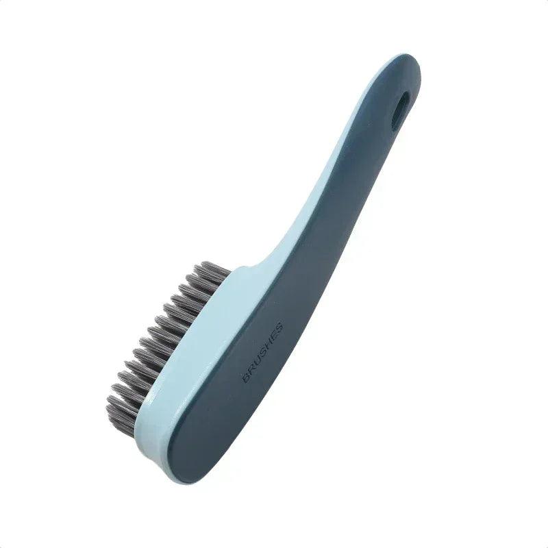Shoe cleaning brush with light blue handle and gray bristles, angled view