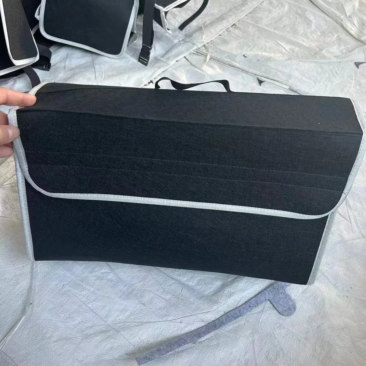 Dark felt car storage organizer box with top handle and white trim along edge