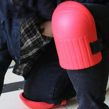 Pink knee pad on dark jeans with black strap and red base.