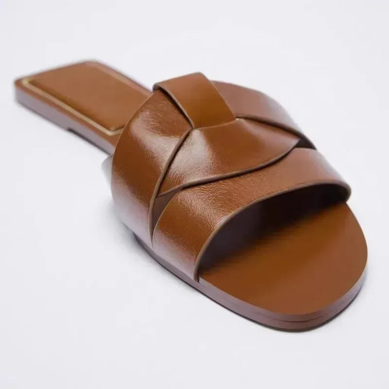 Brown flat slide sandal with two wide crossover straps and open toe