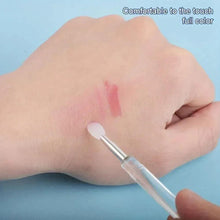 Silicone lip brush applying pink gel swatch on the back of a hand