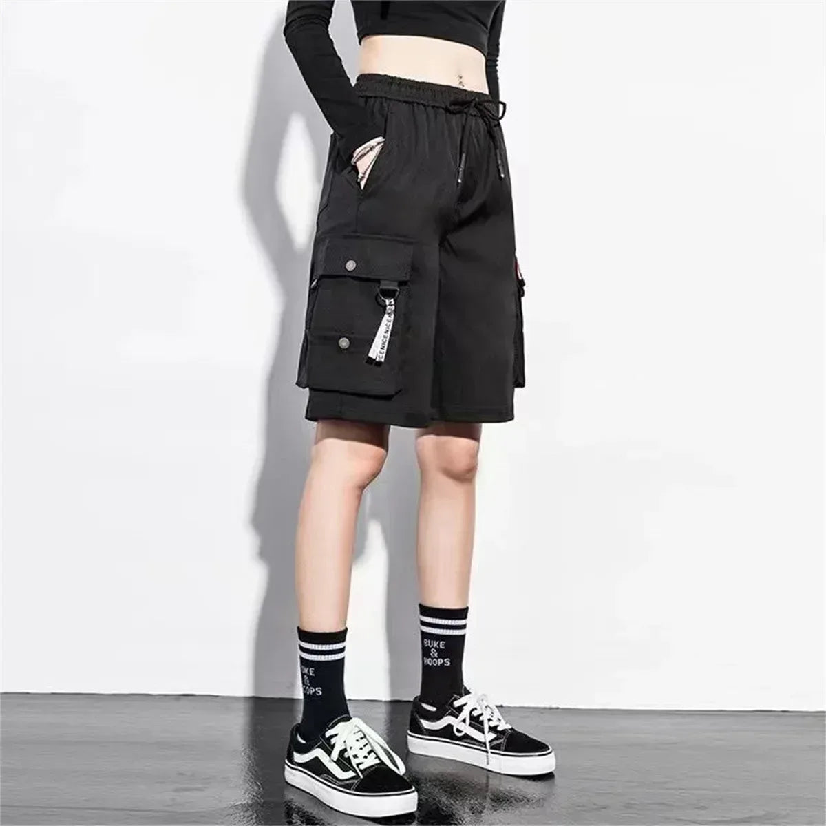 Black cargo shorts with drawstring waist, front flap pocket and hanging strap details.