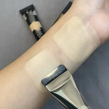 Flat foundation brush with black bristles and silver handle, applying foundation on wrist
