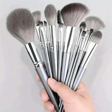 Makeup brush set with silver handles and gray bristles, held in a hand