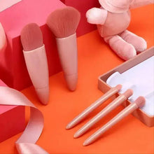 Mini makeup brushes with rose-beige handles beside an open compact case compartment