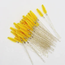 Yellow and white disposable eyelash mascara wands with comb-like bristles on clear handles