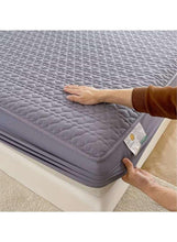 Dark grey fitted topper pulled around mattress corner, hands adjusting edge