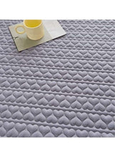 Dark grey quilted topper close-up showing heart-patterned texture and tag