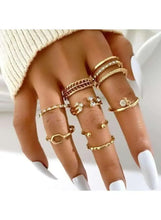 Gold-tone ring set on hand, stacked textured bands with small stones