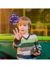 Child holding a multicolour rubber bounce ball with other balls nearby